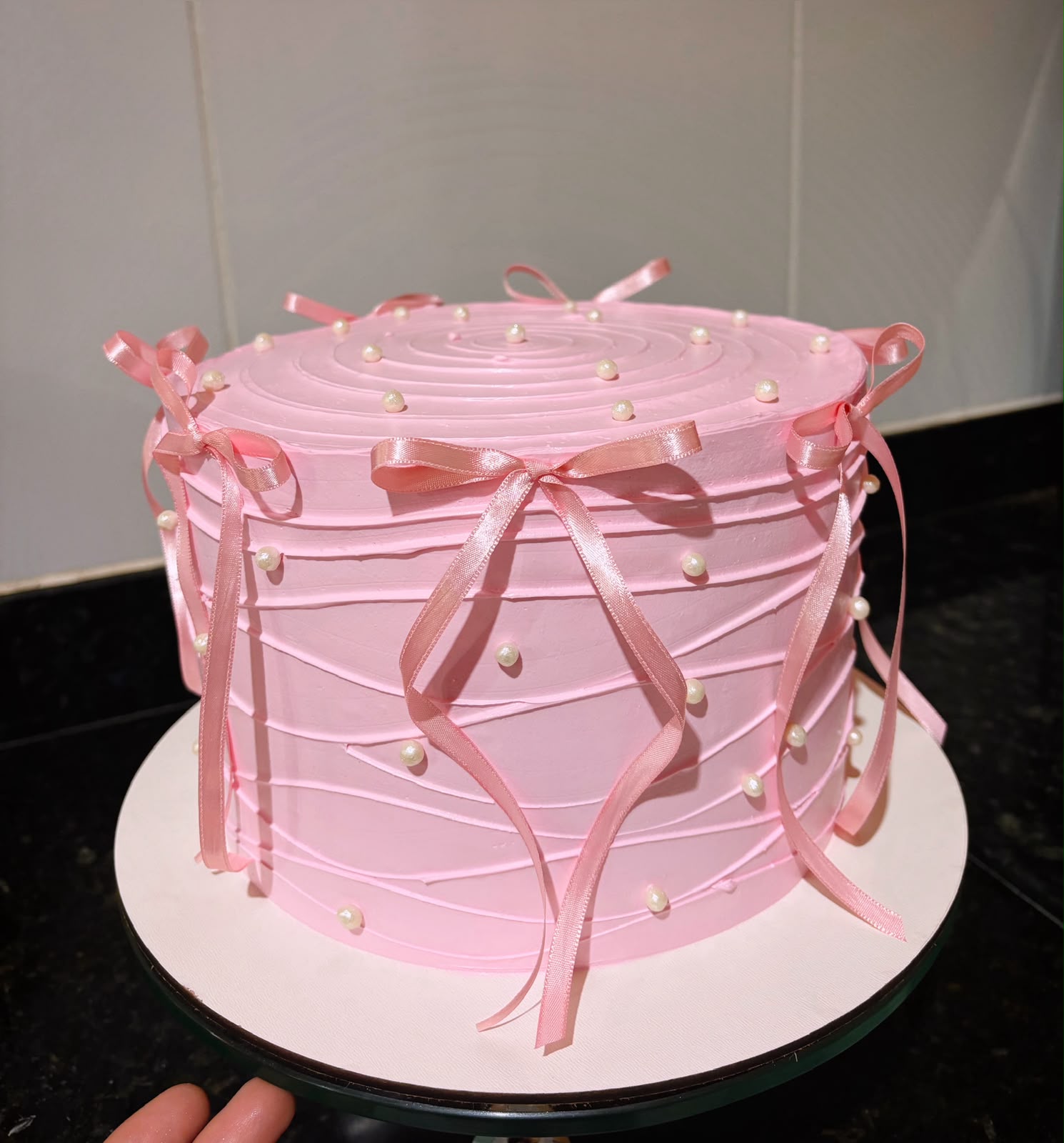 Bolo rosa com laços de cetim e pérolas